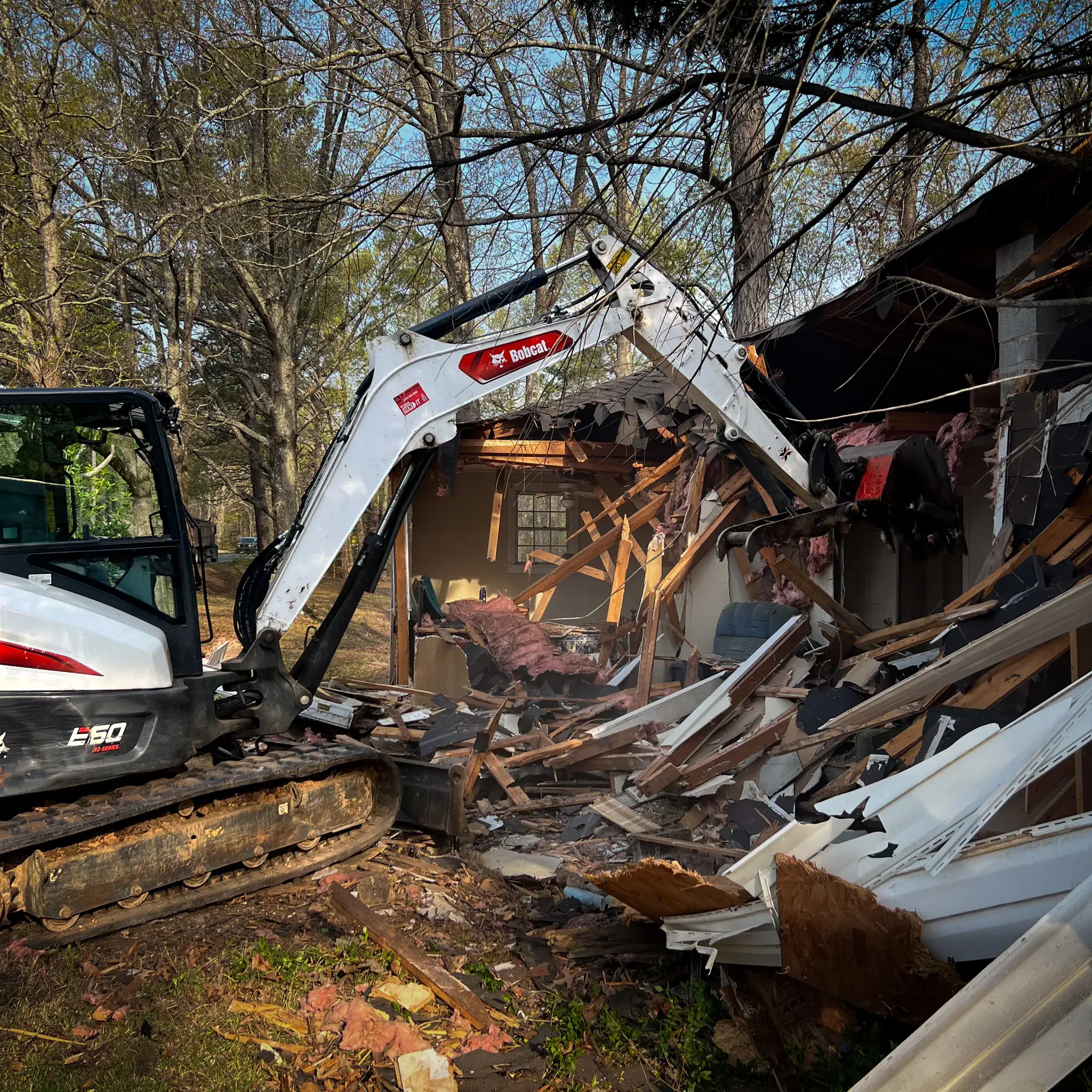 Excavator performing residential demolition