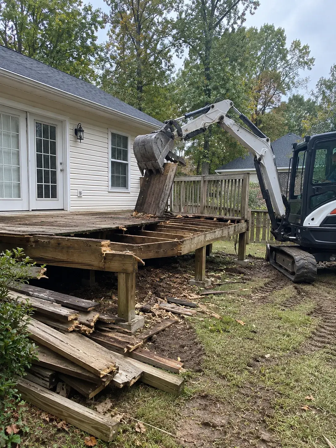 Mini excavator removing a weathered backyard deck